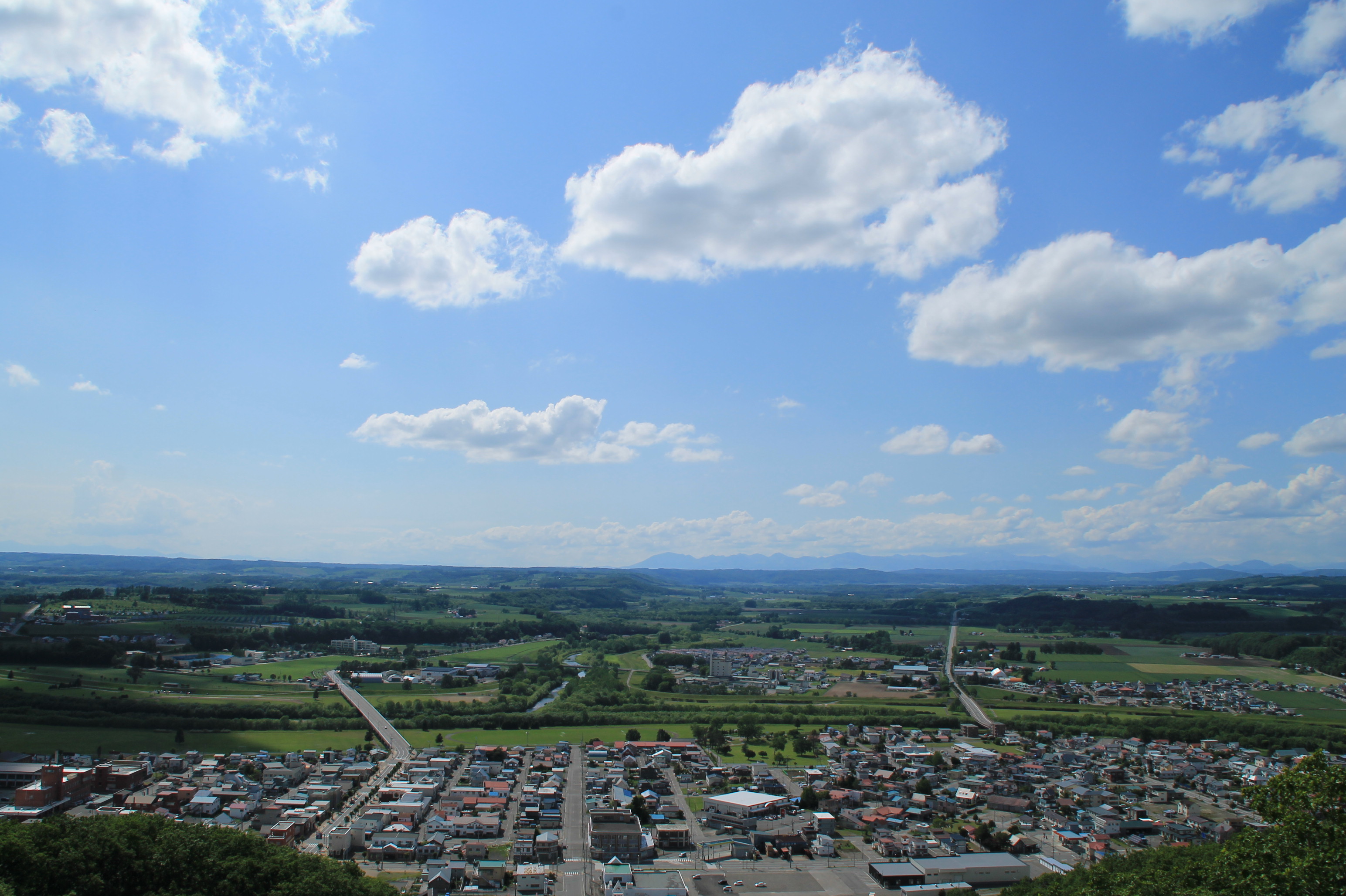 青空の下に広がる本別町の町並みと、十勝の緑豊かな大地